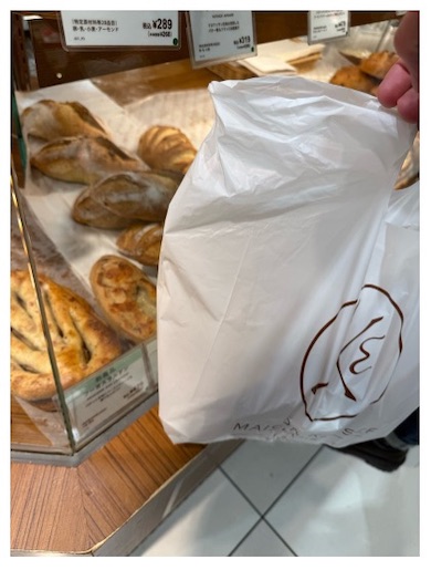 白い袋を掲げる杉浦さん