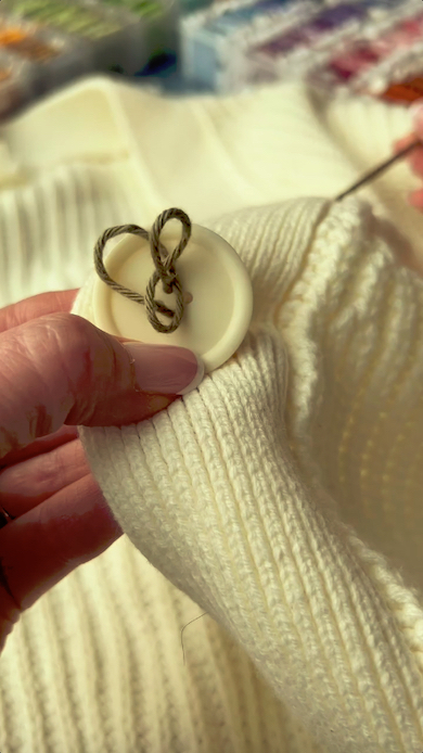 白いボタンに茶色の糸を通しているところ