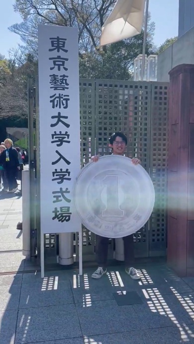 東京藝術大学入学式場の前で1円玉の作り物を掲げる投稿者