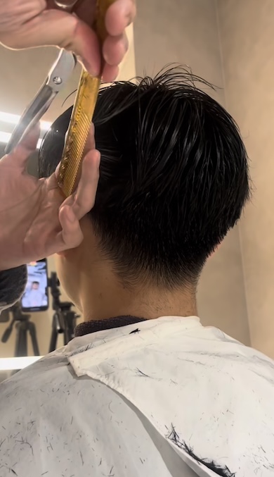 美容師が男性の髪の毛をカットしている様子