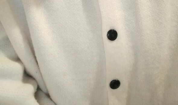 カーディガンのボタンが写っている