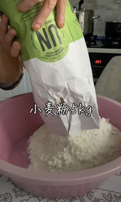 ボウルに小麦粉を入れている様子。テロップで「小麦粉5kg」と表示されている