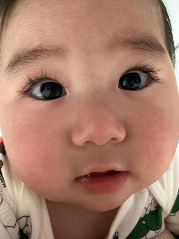 顎に手を添えてポーズをとるふさふさまつ毛の赤ちゃん