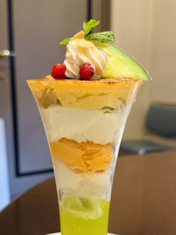 「メロン＆ココナッツのブリュレパフェ」を横から見て具材を映した写真 ／ ロイヤルホスト Fresh Melon Dessert 2025
