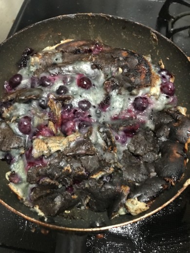 焼きすぎて焦げたブルーベリーホットケーキ。表面は黒く焼け焦げており、生地がうまくひっくり返せなかった様子で全体が崩れている。