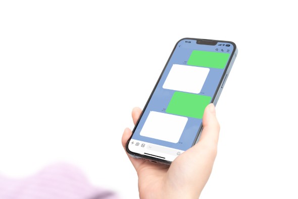 手に持ったスマートフォンの画面に、LINEのようなチャットアプリの会話画面が表示されている