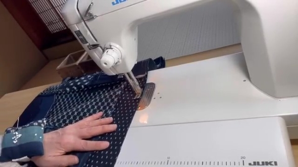 ミシンで布を縫う女性