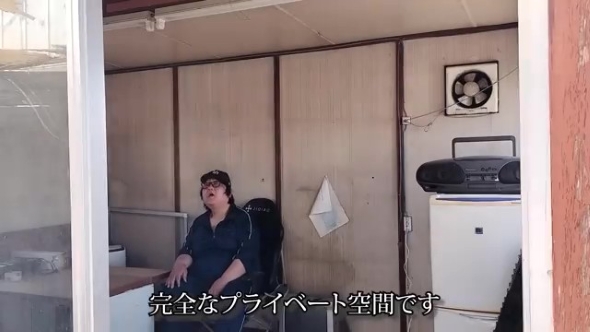 プレハブ小屋で座る男性
