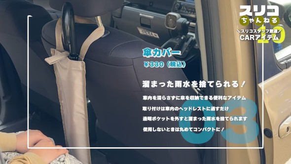 車のシートのヘッドレストに取り付けられた傘用カバーに長傘を収納している様子。商品名『傘カバー』、価格は税込330円と表示されており、車内を濡らさずに傘を収納できる便利アイテムとして紹介されている。