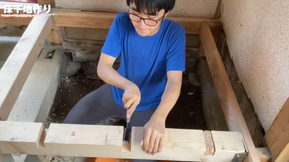 床下地を作るため木材に溝を掘っている息子