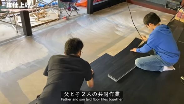 黒いフロアタイルを貼る父親と息子