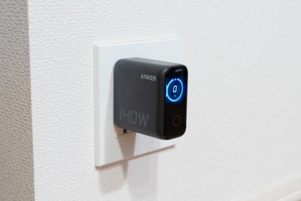 壁のコンセントに差し込まれたAnkerの急速充電器。側面には「140W」と表示され、正面のディスプレイには青い円形インジケーターと「0W」と出力が表示されている。
