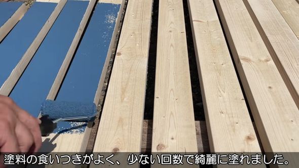 青いペンキで木材を塗っていく様子